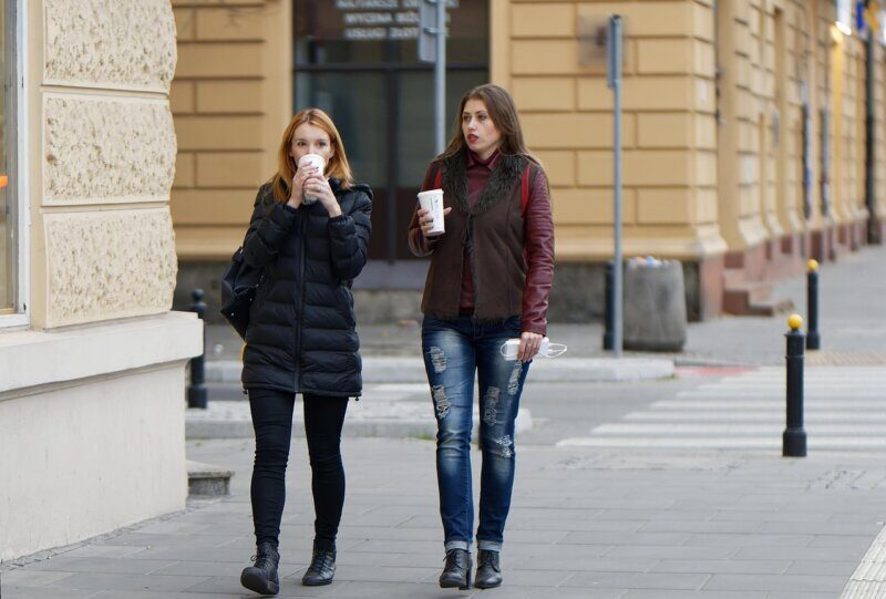 Opusteno druzenje dve prijateljice uz kafu na gradskim ulicama.