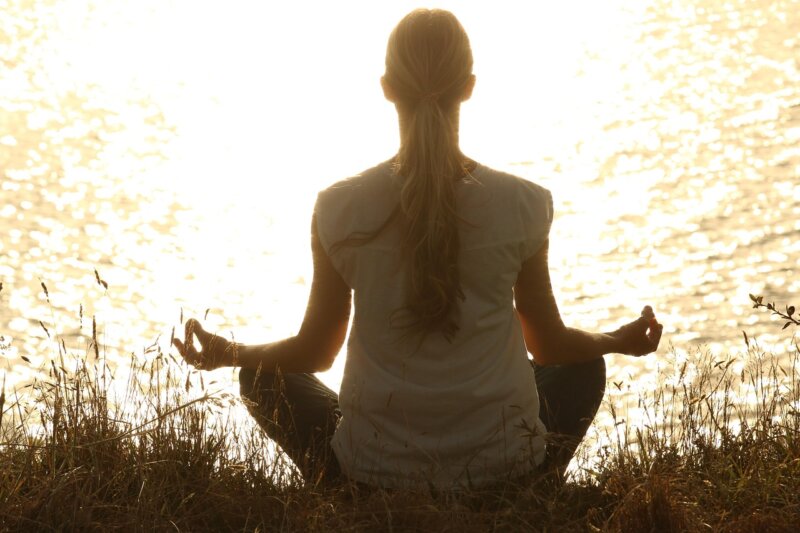silhueta žene koja meditira u prirodi tokom zalaska sunca