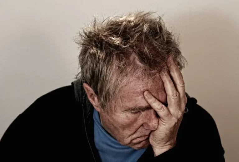 Izbliza portret starijeg muškarca koji pokazuje znakove frustracije i iscrpljenosti dok sedi i drži glavu rukama