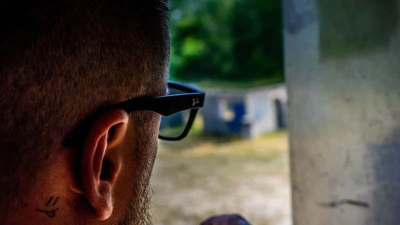 Muškarac sa naočarima za sunce gleda kroz prozor zamišljeno stojeći u praznoj ulici