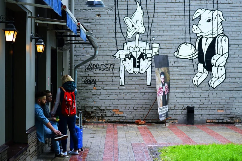 Grupa mladih ljudi sedi zajedno u pauzi, pažljivo slušajući i razgovarajući u opuštenoj atmosferi sa plavim dimom u pozadini