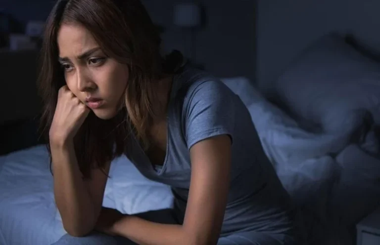 Žena sa izrazom tuge i umora na licu koja gleda niz prema podu